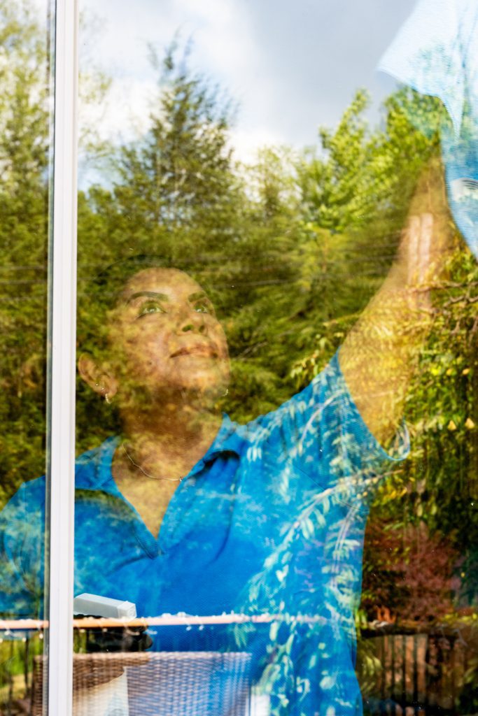 Professional housecleaner washing interior window glass during a detailed deep cleaning service