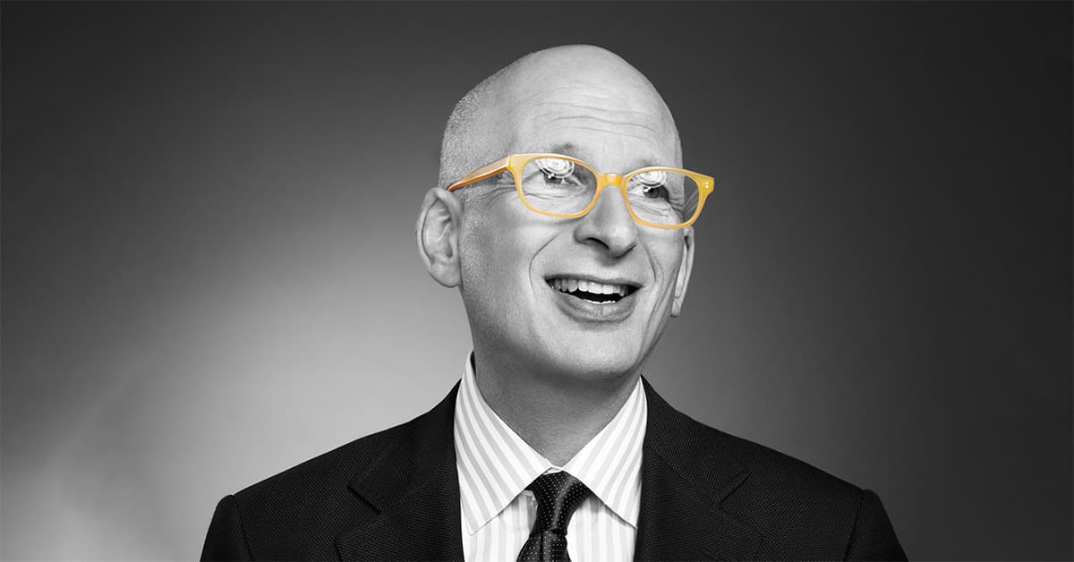 Black-and-white portrait of a Seth Godin wearing bright yellow eyeglasses.