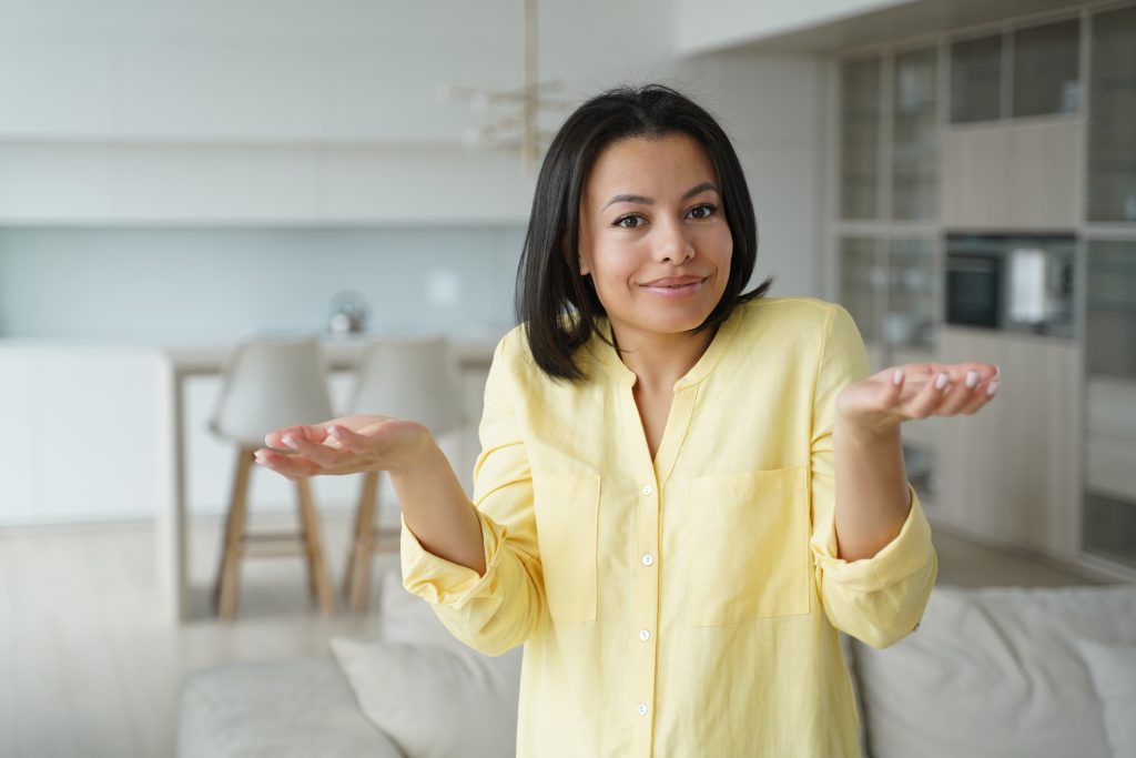 Person shrugging in a clean, modern home, illustrating the question of what goes into the price of house cleaning.
