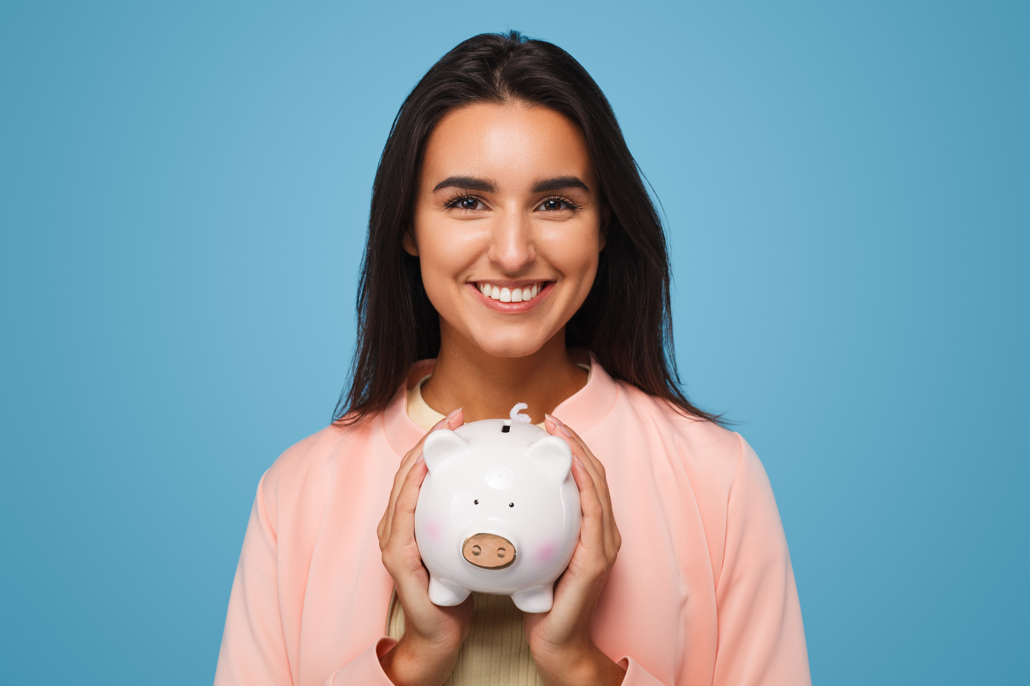 Woman smiling while holding a piggy bank, representing ways to save money on house cleaning.