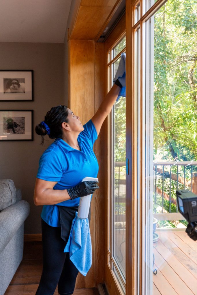Professional house cleaner working in a home, illustrating the choice between local cleaners vs national franchises.