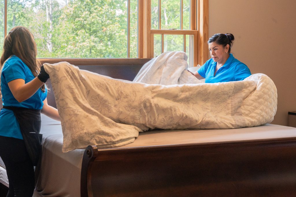 Clean home sleep better — professional cleaners making a bed with fresh linens