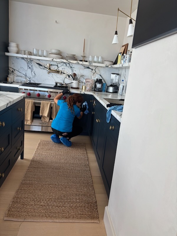 Professional cleaner detailing a kitchen, one of the most time-consuming rooms to clean