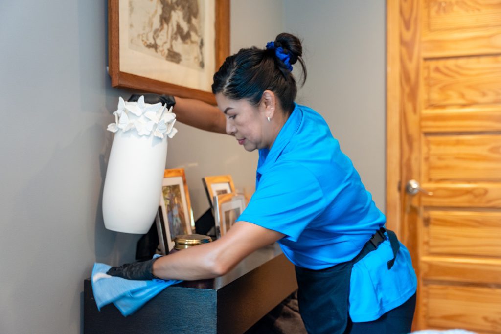 Professional cleaner dusting during basic house cleaning