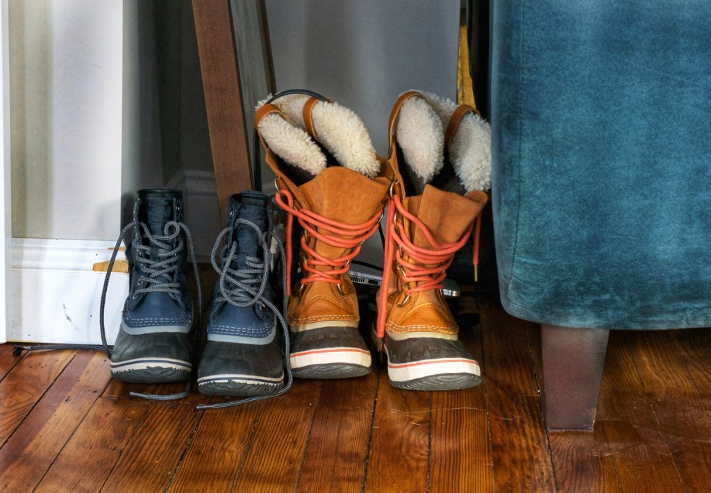 Winter boots by an entryway mat with salt and slush that can damage hardwood floors